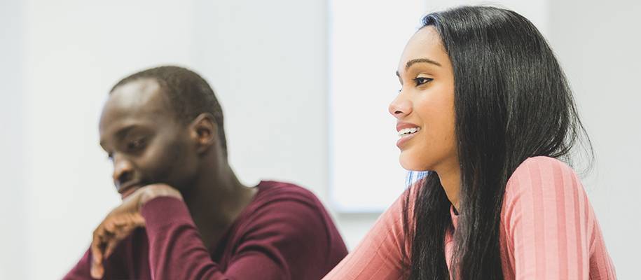Dark-haired, light-skinned girl in pink sweater with dark-skinned man in red swe