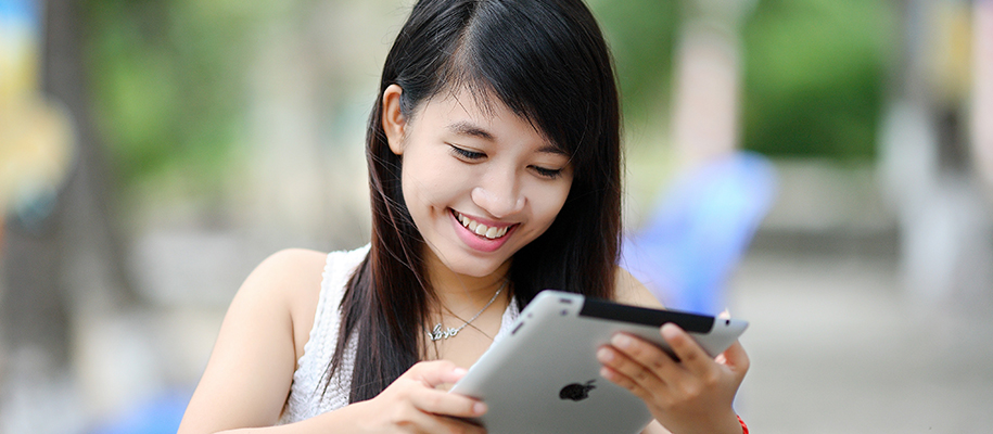 Asian woman in white shirt looking at an ipad out in public