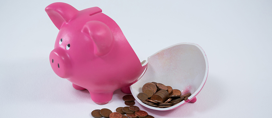 Broken bright pink piggy bank with pennies on white background