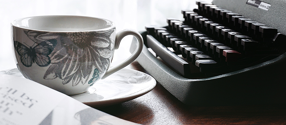 Typewriter, flower and butterfly print teacup, and corner of magazine 