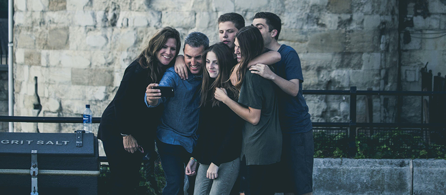 White family of six standing in front of stone building taking a selfie