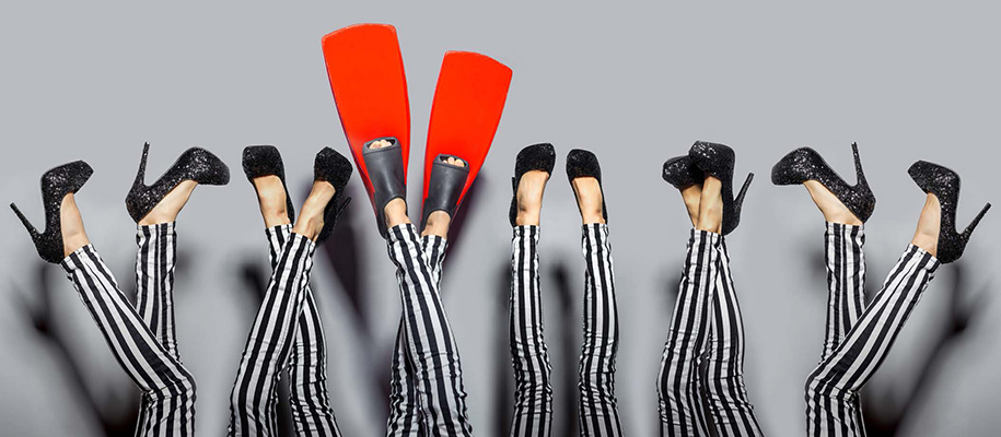 Woman's legs in striped pants and black heels repeated, one with red flippers