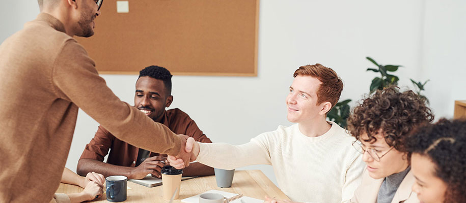 Diverse group of coworkers with two males shaking hands over table