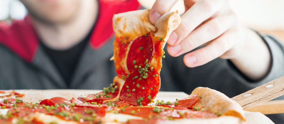 Thin-crust pepperoni pizza slice being lifted from whole pie by White male