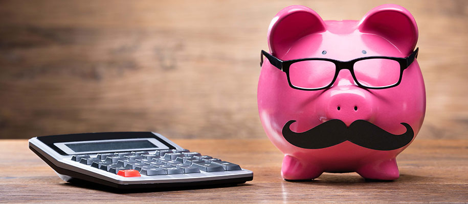 Bright pink piggy bank wearing glasses and black mustache next to calculator