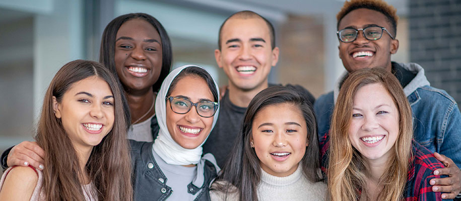 Group of seven diverse college students posing for photo, smiling together