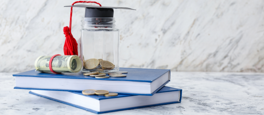 Jar of coins with a graduation cap plus roll of money on a stack of books