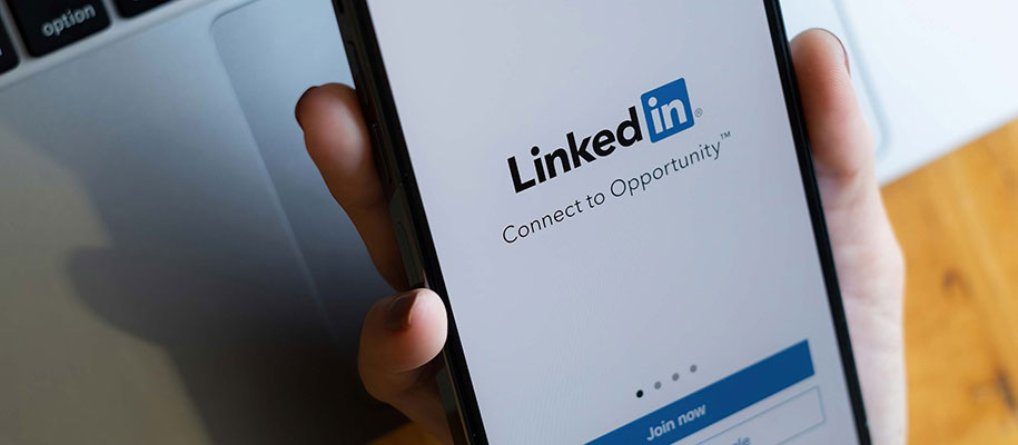 White hand holding smartphone, LinkedIn login, Connect to Opportunity trademark
