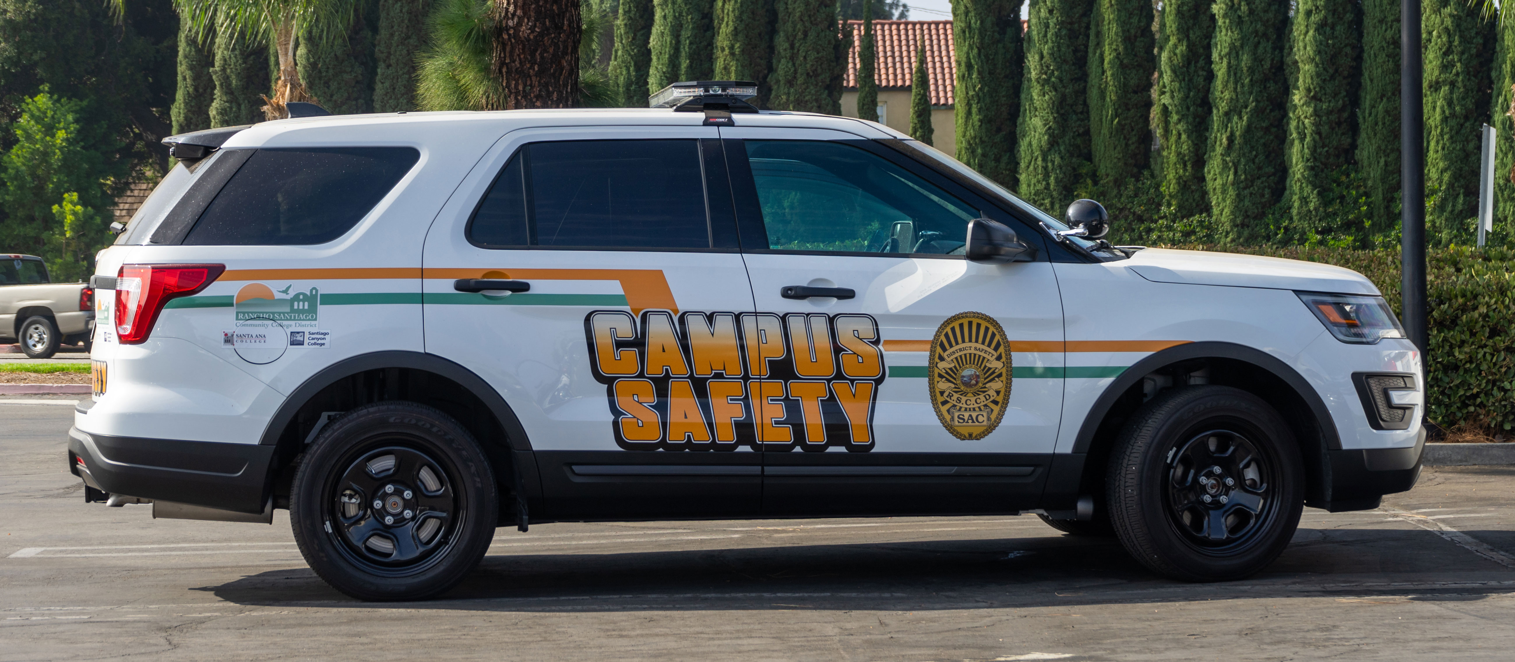 Empty white campus security SUV in parking lot near trees
