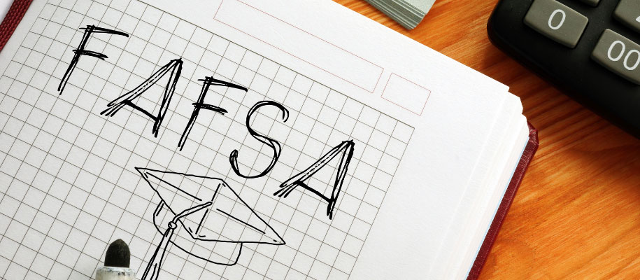 FAFSA and grad cap drawn in graph paper notebook with marker next to calculator
