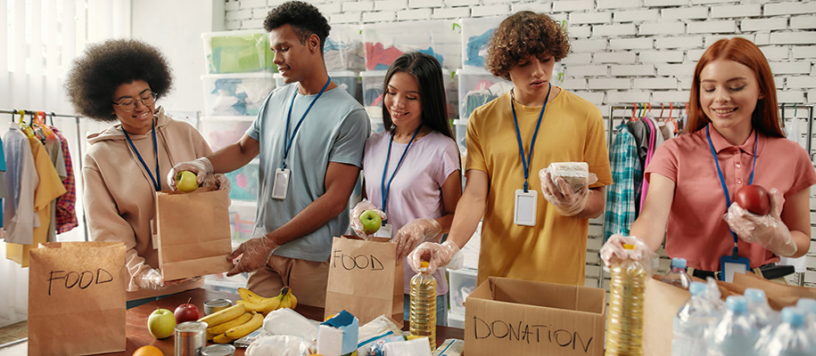 Group of diverse students sorting food and medicine into donation bags and boxes