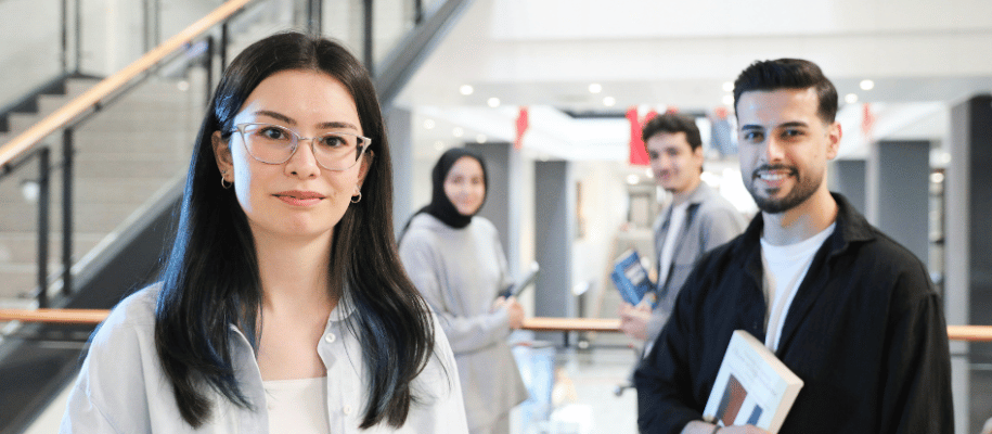 Four adult students standing in a hallway looking at the viewer