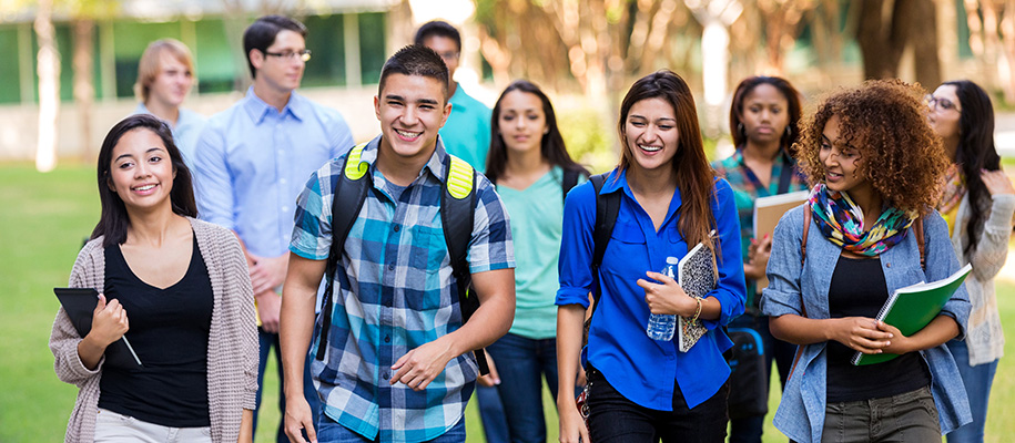 Diverse students walking in big group on campus with backpacks and books