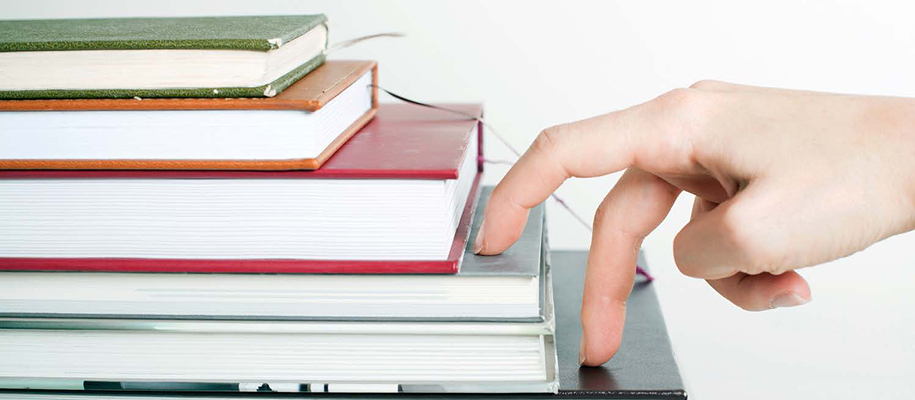 Hand of White person walking fingers up stack of books set up like stairs