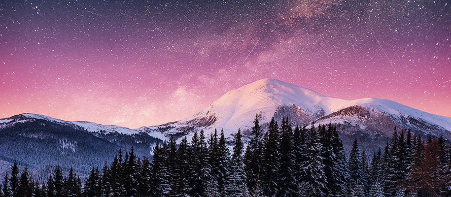 Snowcapped mountains with trees under purple and pink star-filled night sky