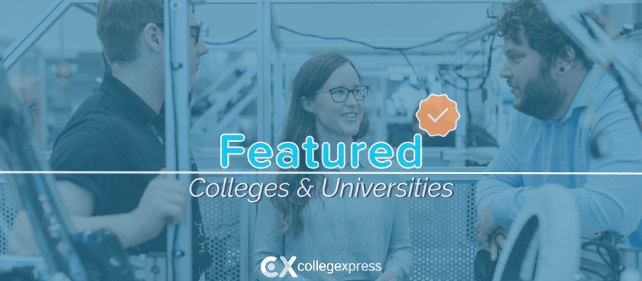 Two men, woman standing in workshop next to metal vehicle, featured schools logo