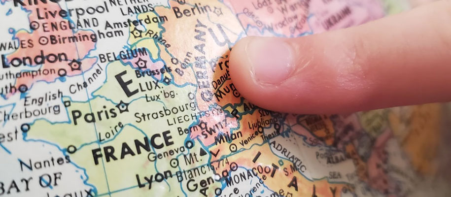 Closeup of White finger pointing at Germany on colorful globe showing Europe
