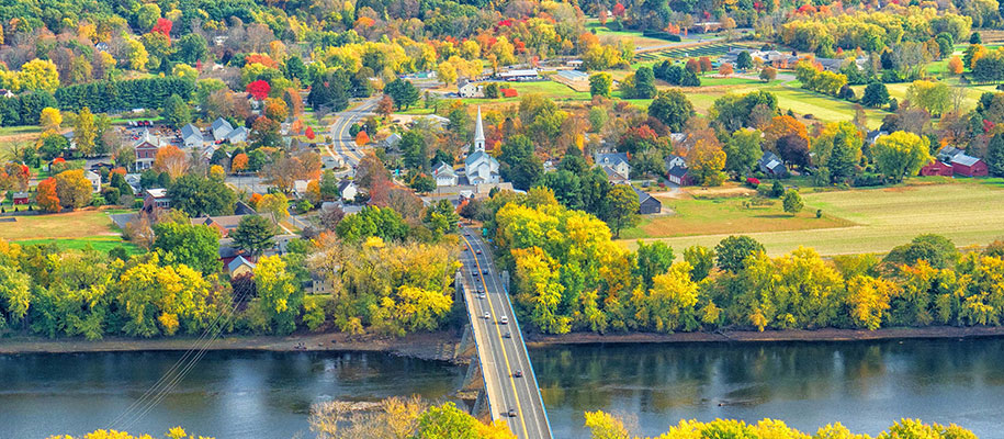 Overhead shot of New England village in the fall with river, church, foliage