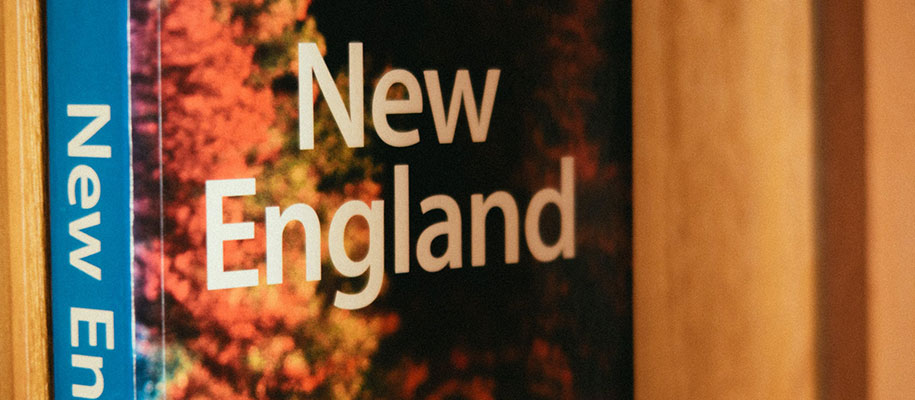 Closeup of New England travel book sitting on wooden bookshelf