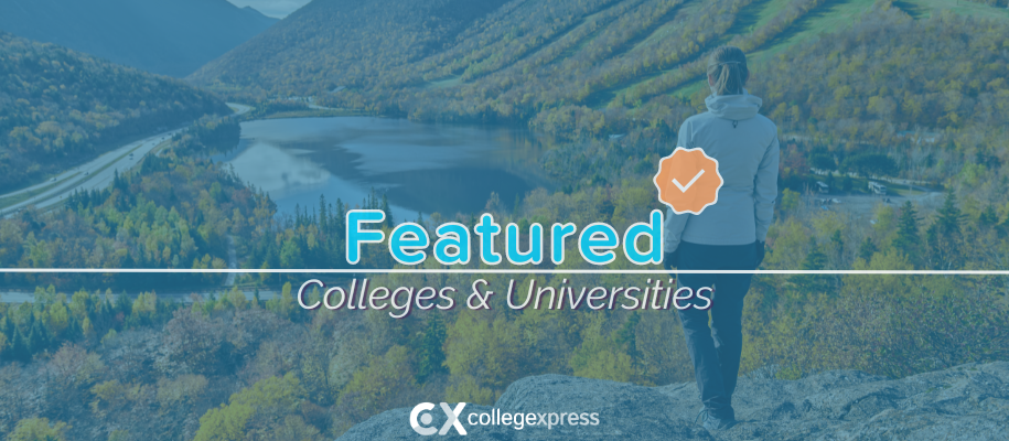 Woman in grey coat stands on rock, fall trees on mountain, featured schools logo