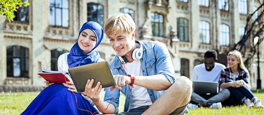 Woman in blue hijab smiling at table held by White man with headphones