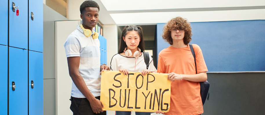 Black male, Asian female, and White male in school hallway with Stop Bullying si