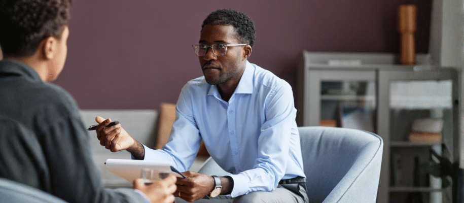 Counselor holds a notepad and sits across from a student in an office