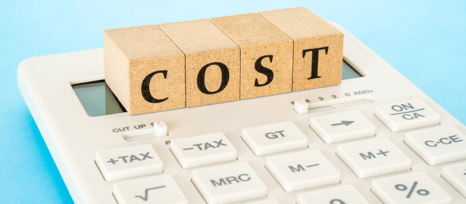 Close up of a calculator with wood blocks on top spelling out "cost"