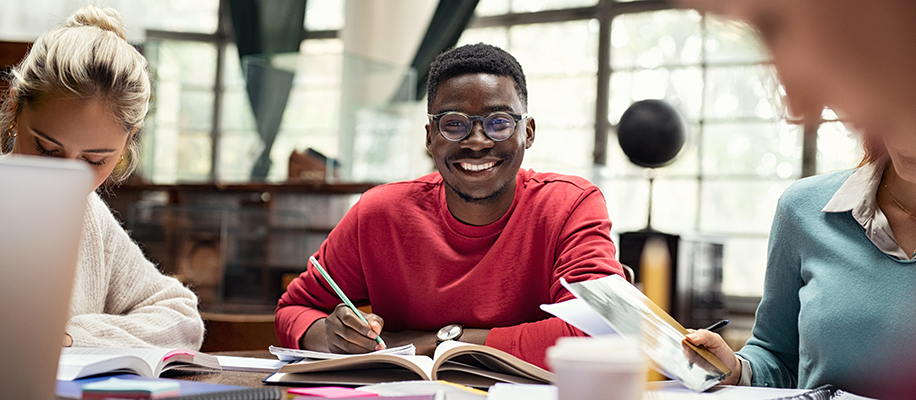 Smiling Black man in glasses and red shirt doing research with group in a study