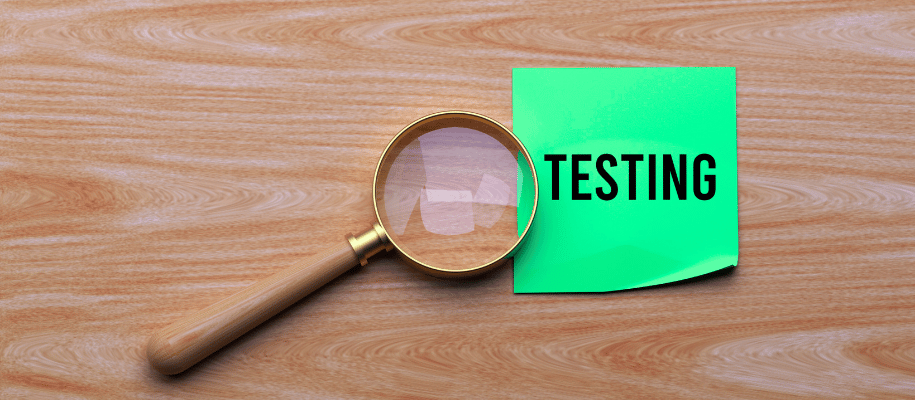 Magnifying glass resting on a sticky note with the word "testing" on it