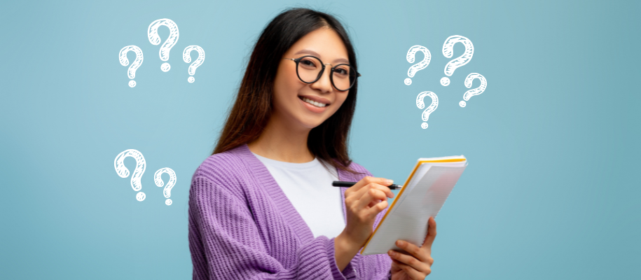 Asian woman in glasses and purple sweater writing questions on notepad