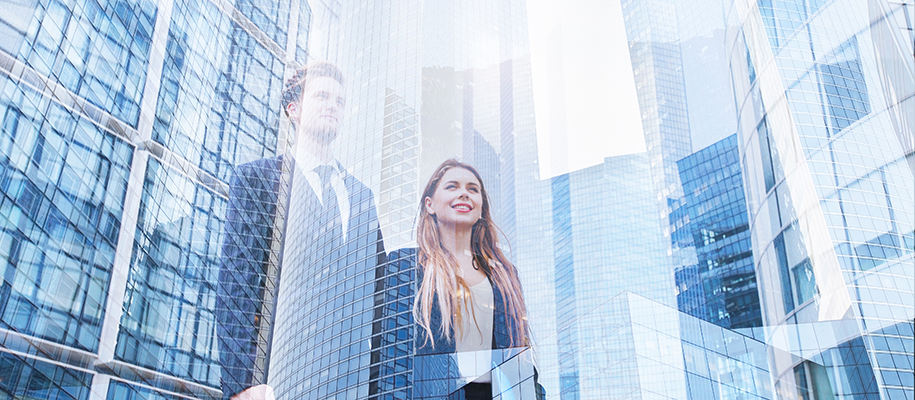 White man and woman in business suits look inspired by overlay of tall buildings