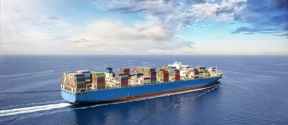 Cargo ship carrying shipping containers of varying colors under cloudy blue sky