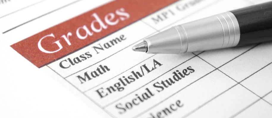 A wooden letter A leaning against a pot with flowers with blurry lights behind