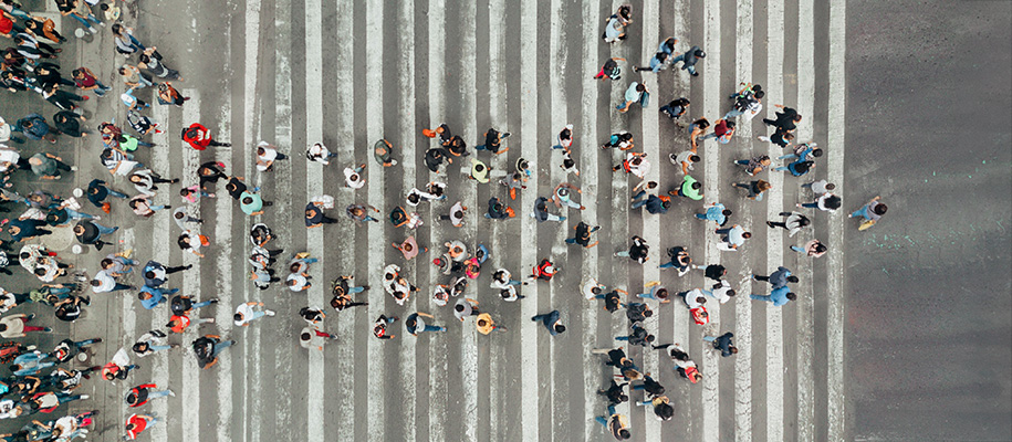 Group of people crossing a crosswalk in the shape of an arrow