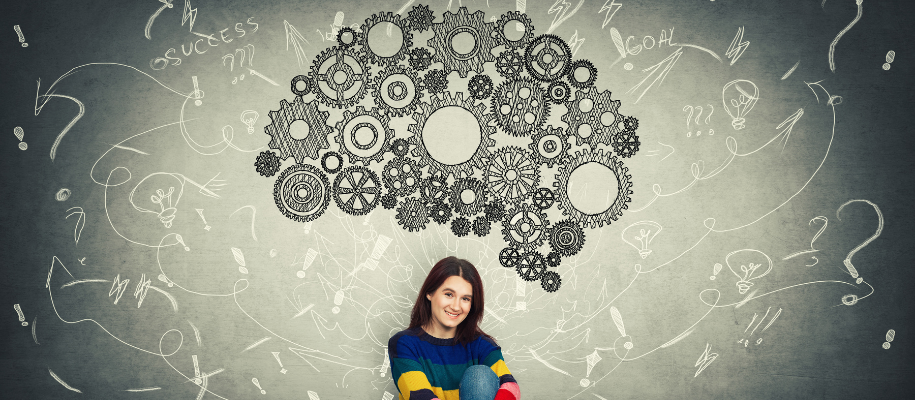 Young white woman in colorful sweater sitting below drawn cogs in shape of brain