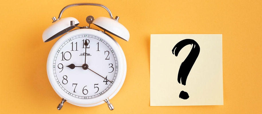 White alarm clock and sticky note with question mark on yellow background