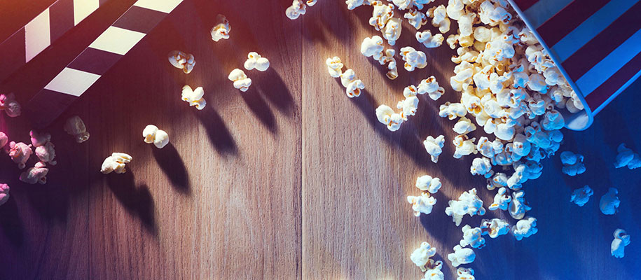 Spilled popcorn and movie clapper on desktop with dramatic lighting