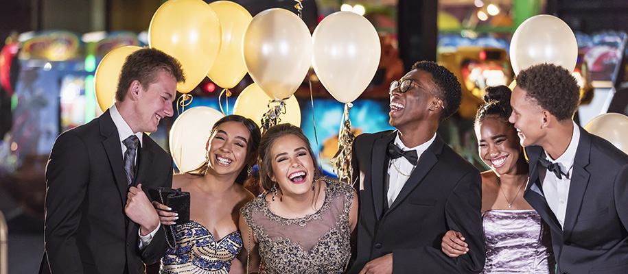 Happy group of diverse seniors at prom in fancy suits and dresses