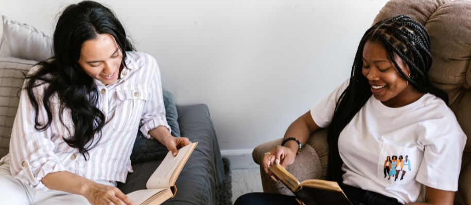Hispanic woman and Black woman hanging in dorm reading books together