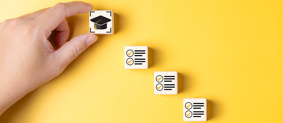 Hand of white person reaching for cube with grad cap above cubes with checklists