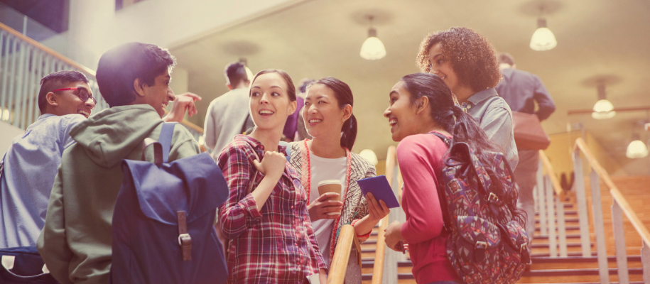 Group of diverse students standing on stairs in college campus building