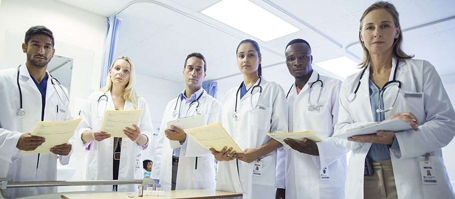 Group of diverse doctors and medical residents observing patient at bedside