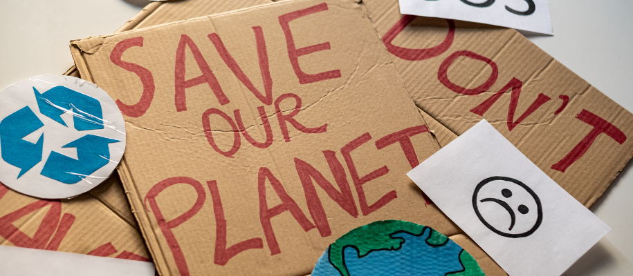 Cardboard protest signs that say Save Our Planet with recycling symbol