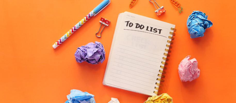 To-Do List written on notebook surrounded by crumbled paper & office supplies