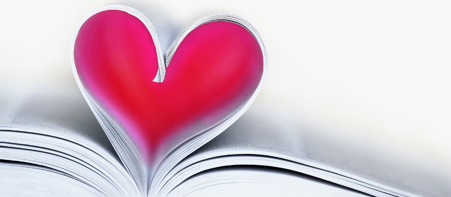 Closeup of white pages in a book curled into a heart shape, shaded red inside