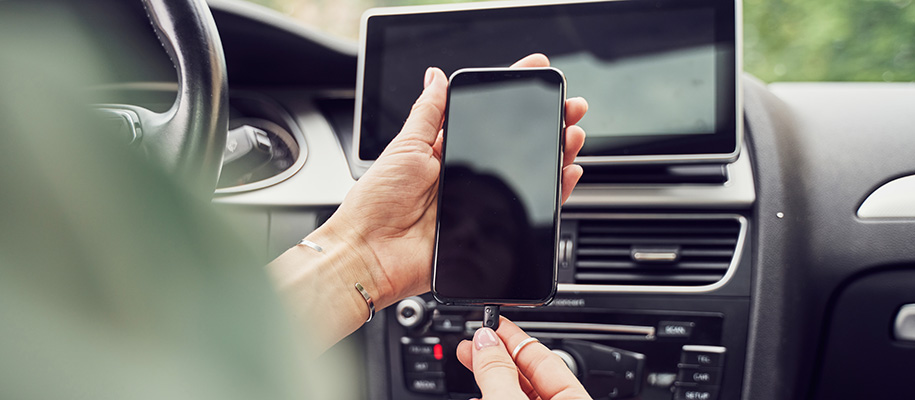 Body of White woman holding dead phone with left hand and plugging in charger with right