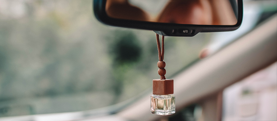 Square glass and wood air freshener hanging from a car's rearview mirror