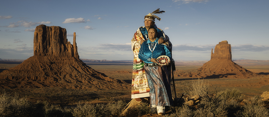 Navajo couple in traditional dress looking into distance of western plateau