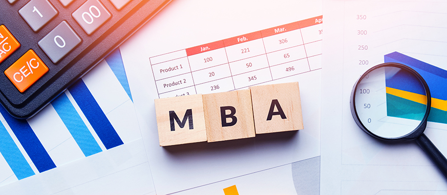 Wood blocks spelling MBA with calculator, business papers, magnifying glass